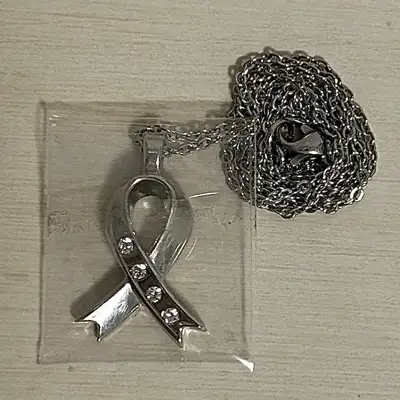 Brand new, never worn; this silver coloured pendant necklace features an elegant Breast Cancer Aware...