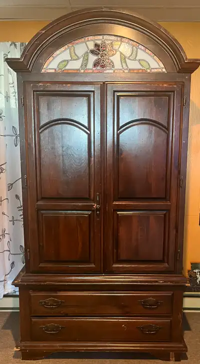 solid wood armoire with a decorative stained glass accent, providing ample storage with its drawers...