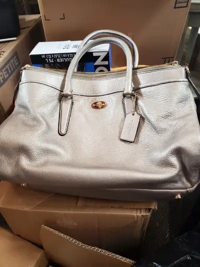 A shiny metallic leather tote bag from Coach. It's a stylish and spacious handbag. Made with genuine...