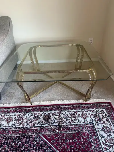 Add a touch of elegance to your living space with this stylish glass and gold coffee table! This use...