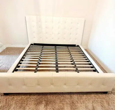 White leather bed frame has a leather headboard and matching footboard. Frame includes a wooden slat...