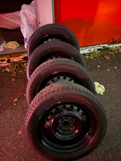 Get ready for winter with this set of four pre-owned Michelin X-Ice Snow SUV tires mounted on black...