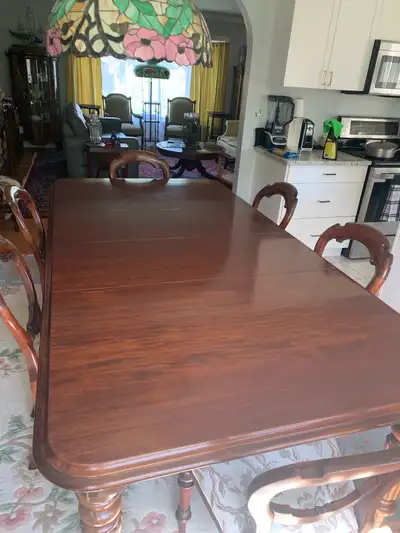 This beautiful, used dining table and chairs set features a rich, dark wood finish, exuding classic...