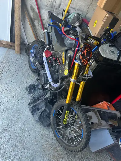 This is a dirt bike, featuring a durable frame, off-road knobby tires, ProTaper handlebars, gold-fin...