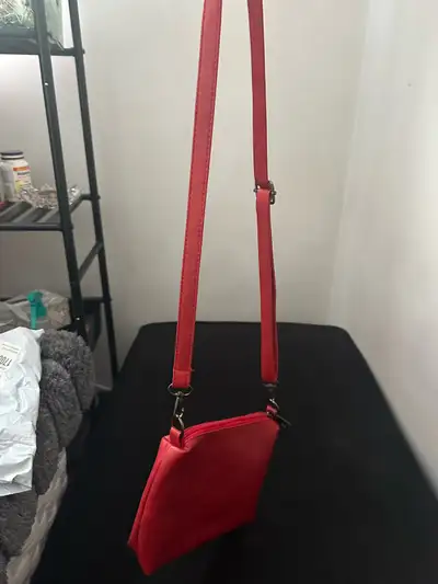 Un petit sac rouge avec une bandoulière., View more