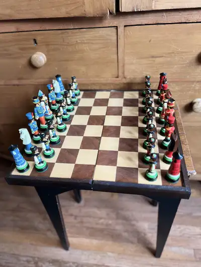 This is a vintage chess set with unique, hand-painted pieces depicting soldiers and royalty; it is u...