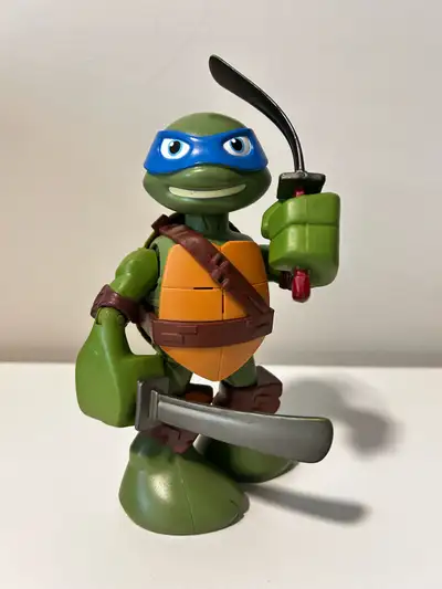 Green action figure with blue mask and orange chest plate. Toys/2