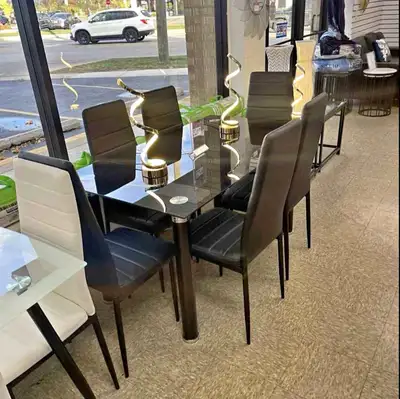 This elegant 7-piece dining set features a sleek glass table and six black faux leather chairs, perf...