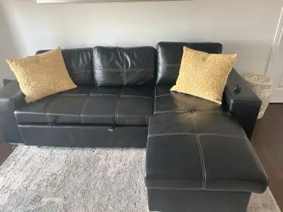 This is a used black faux leather sectional sofa with a pull out bed, perfect for adding extra sleep...