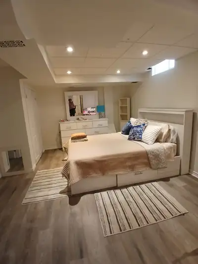 Large, modern, furnished room in a bright, clean basement of a detached family home. The room has tw...