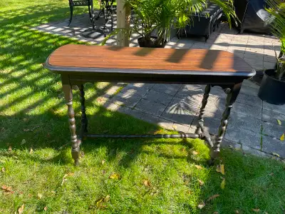 This elegant antique hall table features a rich, dark wood finish and classic turned legs, making it...