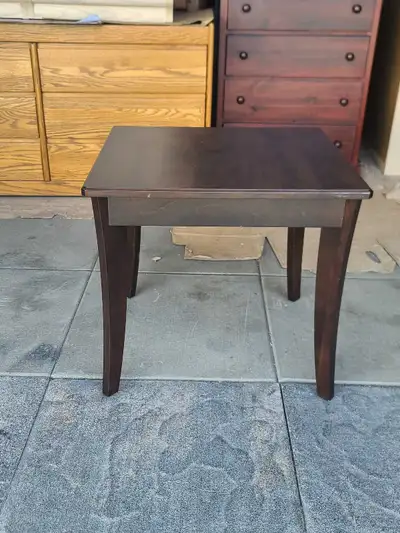 Dark brown wood end table has a square top and four tapered legs. The solid wood construction featur...