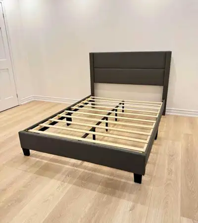 This full-size bed frame features a sleek, dark grey upholstered headboard and sturdy wooden slats,...
