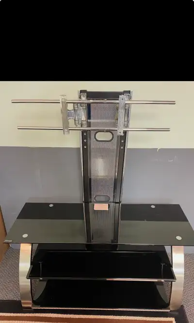 This sleek, used TV stand features black glass shelves and a sturdy metal frame, offering a modern l...