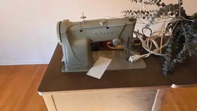 Vintage Singer sewing machine with original wooden sewing table. Solid metal machine with built-in s...