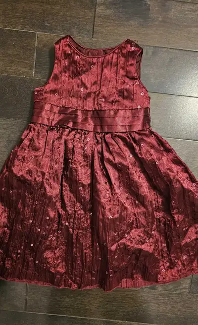 This girls dress features a maroon, crushed velvet-style fabric with sequin detailing and a ribbon t...