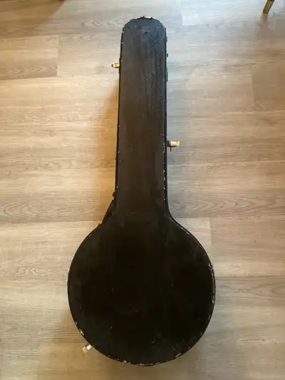 Black banjo hard case with grey interior. Storage compartment for strings and picks. There are some...
