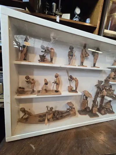 This shadow box features a collection of Nigerian Thorn wood carvings depicting various figures and...