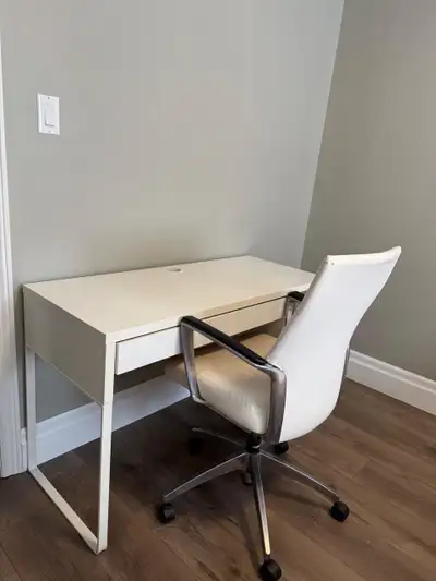 Modern white IKEA MICKE desk with a metal frame and a matching white faux leather office chair. The...