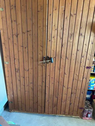 This is a used wooden storage cabinet, perfect for organizing your garage or shed. The cabinet featu...