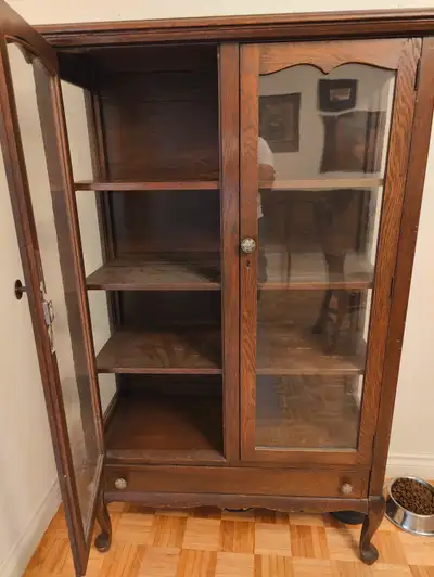 The item in the image is a vintage wooden display cabinet or curio cabinet. Here is a detailed descr...