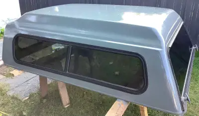 Fiberglass truck cap, features sliding side windows with screens. The cap includes a framed glass re...