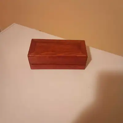 I'm selling a small, charming wooden box with a reddish-brown stain. It's perfect for storing jewelr...