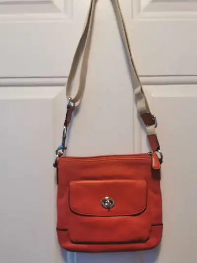 This is a used Coach Park Pebbled Leather bag in orange with dimensions of 10"x10". It's a stylish a...