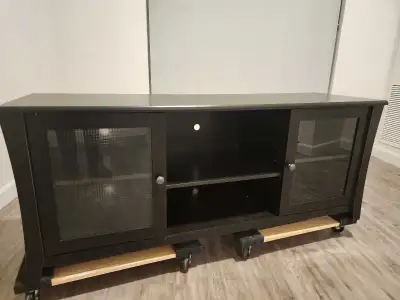 This used TV stand is a sturdy and stylish piece, perfect for any living room. It features glass-pan...