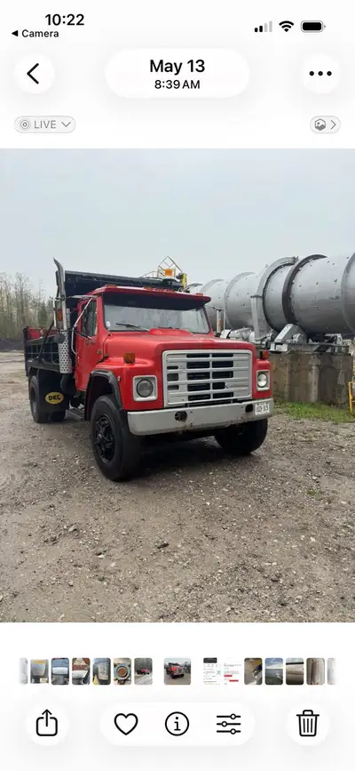 Durable International S-Series dump truck has a red cab and a black steel dump body. This medium-dut...