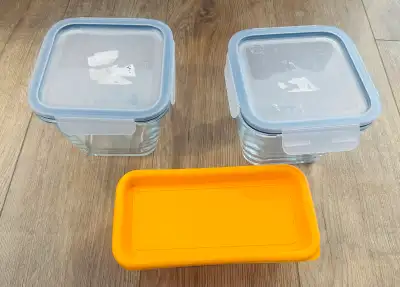 These two square IKEA glass food containers with locking lids and one additional orange rectangular...