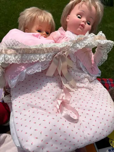 Panier en osier avec deux poupée ça fait comme un lit avec un sleeping bag rose et blanc