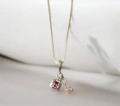 Elegant silver necklace has a 24in box chain with two medical-themed charms. The first charm is a sm...