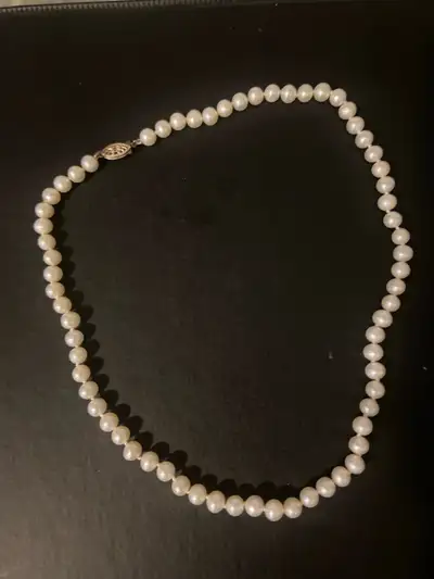 This elegant pearl necklace features lustrous, round pearls strung on a delicate chain, complete wit...