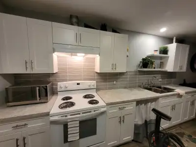 This bright and modern suite features updated flooring, a clean kitchen with white cabinetry, and a...