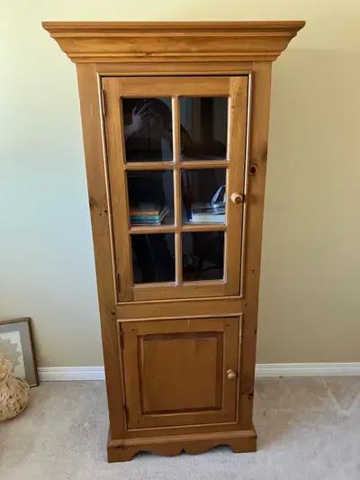 Large wooden cabinet, does not include books seen inside. Upper door has glass window built in. 66”...