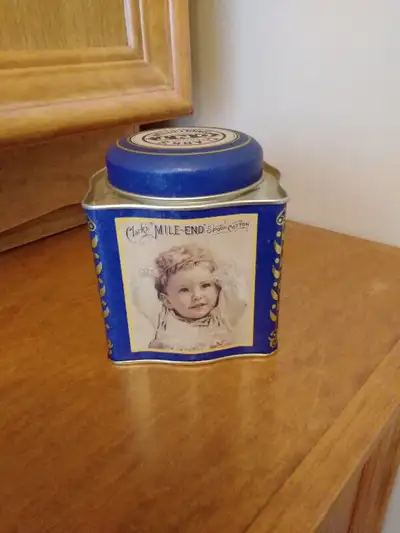 The tin has a picture of a little girl and her dog sitting on a chair together. The other picture is...