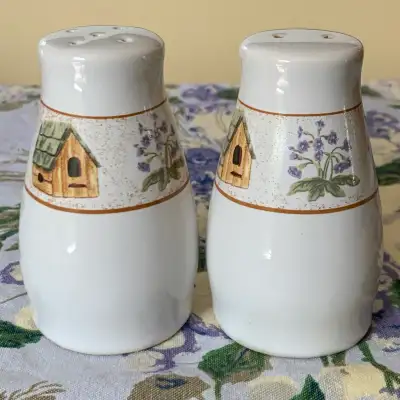 Ceramic salt and pepper shaker set featuring a charming birdhouse and floral motif. A lovely additio...
