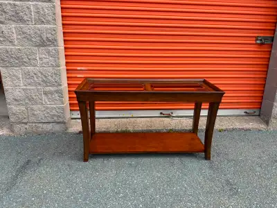 This elegant wooden console table features a sleek design with two glass top insets and a convenient...