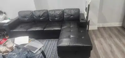 This is a used black leather sectional sofa, perfect for a living room or entertainment area with so...