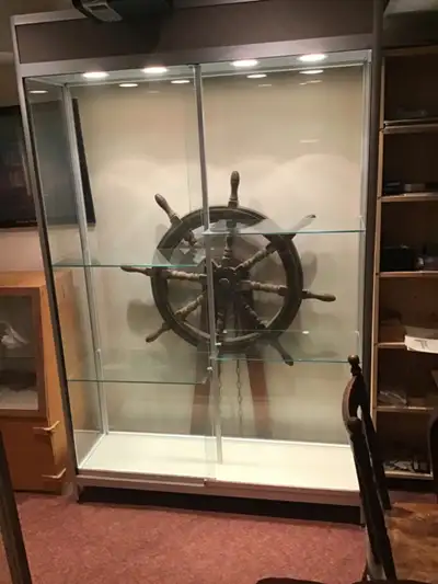A glass display cabinet approx. 6’8” high, 14” deep , 4’ wide. It has 4 moveable glass shelves and t...
