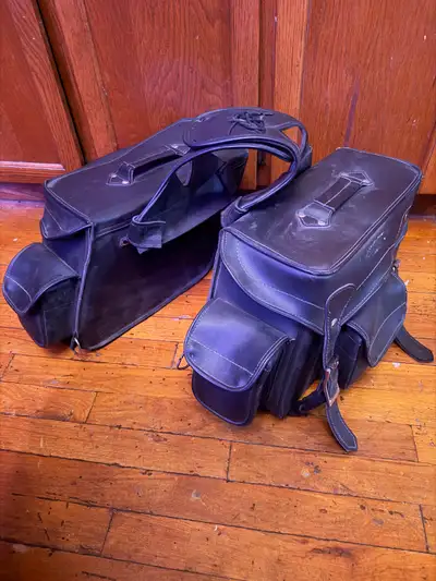 Set of two black leather motorcycle saddlebags. They're made of durable material and feature buckle...