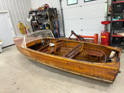Vintage wooden cedar boat with steering wheel and bench seating. Stored in a cottage with some signs...
