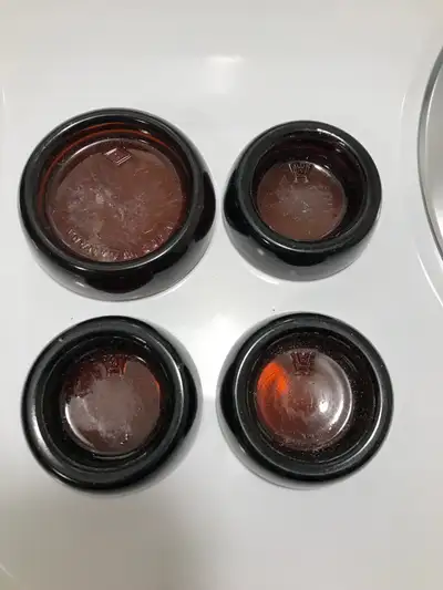 A group of four antique amber glass furniture casters . Three are 2 1/4” inch size amber glass Hazel...