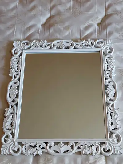 This decorative mirror features an ornate white frame. It's suitable for hanging in any room. Includ...