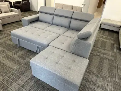 This grey sectional sofa offers a pull-out bed and ample storage. It's upholstered in a durable fabr...