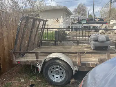 This is a flat bed trailer in used condition. It features a wood deck, metal frame, and a mesh metal...