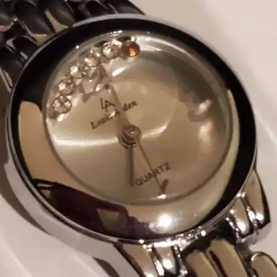 This is a Louis Arden watch with a silver-tone band and a decorative crystal design on the watch fac...