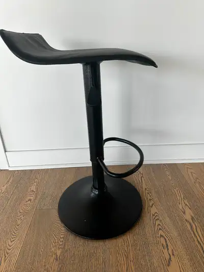 4 tabourets de bar noirs en simili cuir à hauteur réglable.