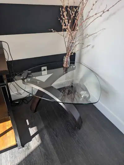 This modern, pre-owned side table features a sleek, clear tempered glass tabletop supported by a uni...